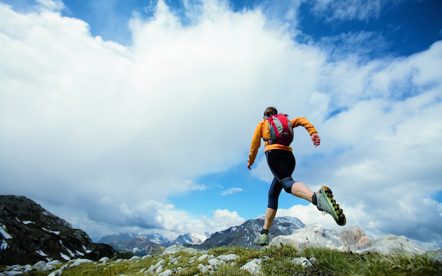 Woman trail running under cloudy skies
